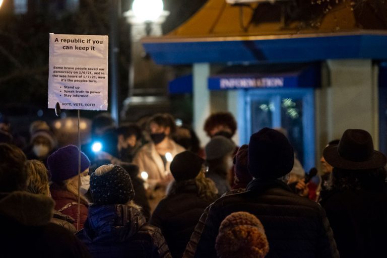 People hold candles and signs at a vigil on Ashland Plaza on Jan. 6. Drew Fleming photo