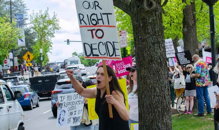 "Bans Off Our Bodies" rally goer Kerul Dyer waves her sign at motorists on East Main Street at the Ashland Plaza on Saturday, May 14. Drew Fleming photo for Ashland.news