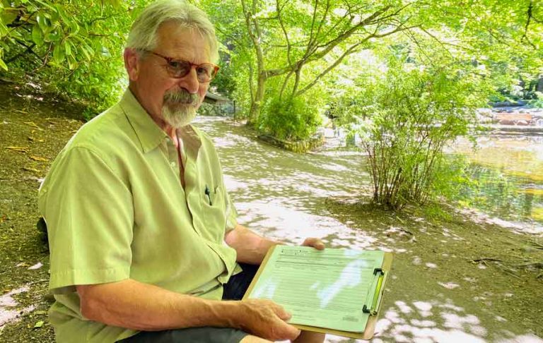 Mike Gardiner holds a clipboard with an initiative petition on it in Lithia Park. Ashland.news photo by Holly Dillemuth