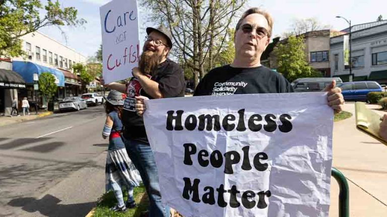 Jason Houk, foreground, a Southern Oregon Jobs with Justice board member, and about 20 others were out on the Ashland Plaza in April showing signs supporting homeless people. Ashland.news photo by Bob Palermini