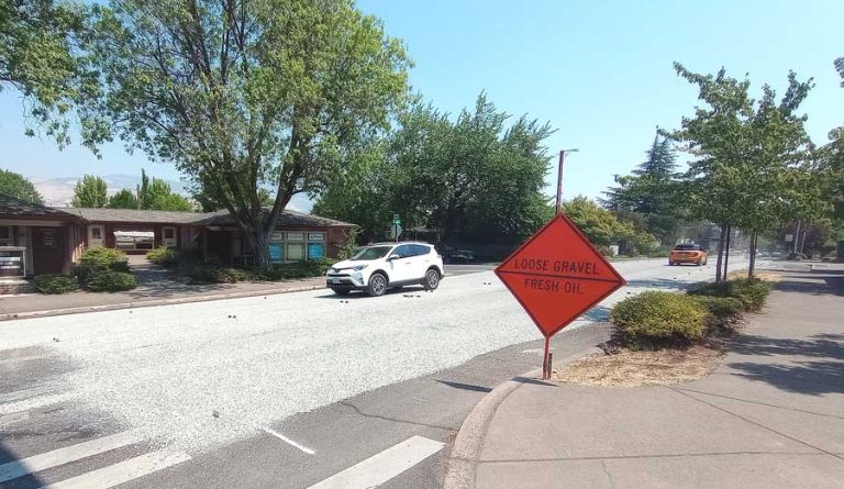 Cars drive over gravel applied to East Main Street at Lithia Way in July as part of a seal coating operation. Ashland.news photo by Morgan Rothborne