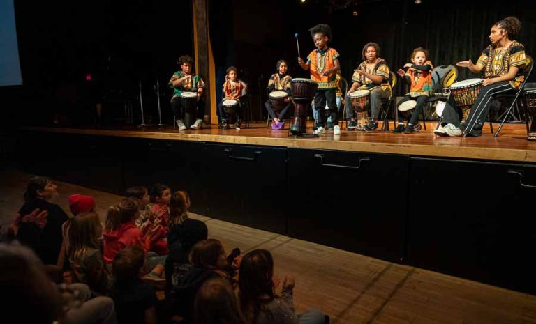 Members of the choirs from Bellview Elementary and TRAILS schools (seated on floor) watch the BASE drummers perform at the beginning of the MLK Day Celebration. Ashland.news photo by Bob Palermini