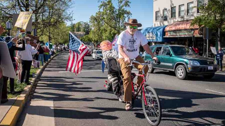 A man riding a bicycle with a cardboard cutout of Donald Trump in prison attire rode through downtown a number of times during the protest. Ashland.news photo by Bob Palermini