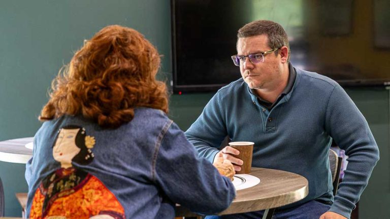 Candace Williams, back to camera, discusses the city budget with Councilor Dylan Bloom at a Coffee & Conversations event in May 2025. Ashland.news photo by Bob Palermini