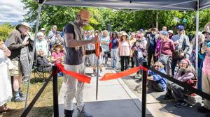 Ashland Artist Micah BlackLight, creator of the plaque artwork, cuts the ribbon for the unveiling. Ashland.news photo by Bob Palermini